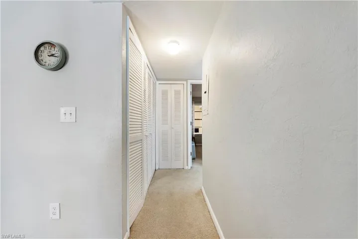 Corridor featuring a textured wall and light carpet