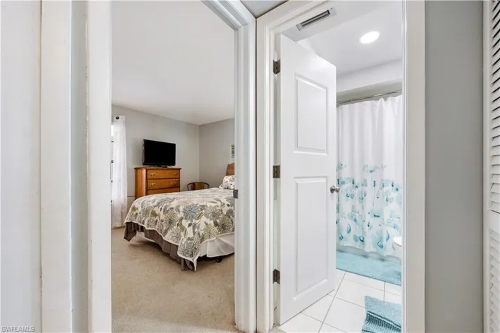 Bedroom featuring light carpet, ensuite bath, and light tile patterned flooring