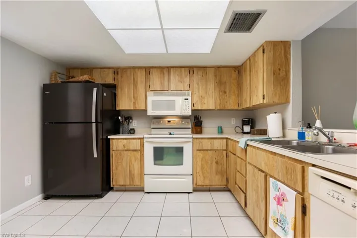 Kitchen featuring light countertops, white appliances, and light tile patterned floors