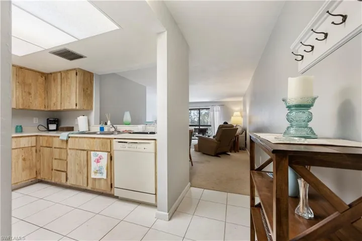 Kitchen with light countertops, dishwasher, open floor plan, light colored carpet, and light wood finish cabinets