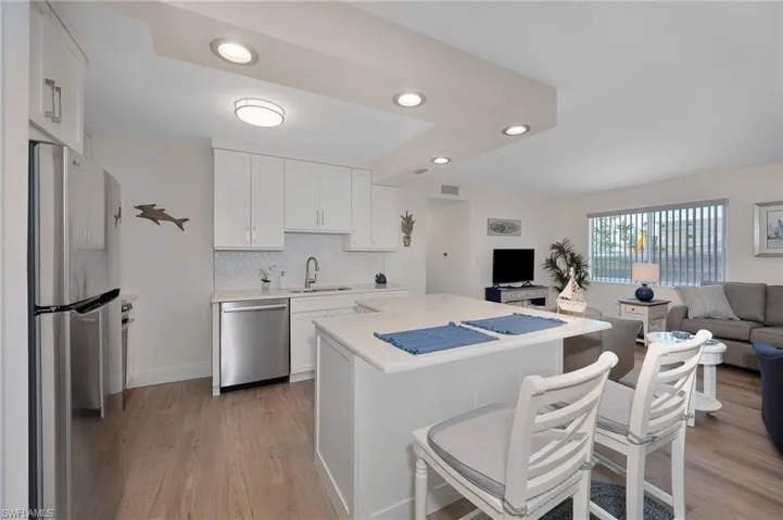 Kitchen featuring light wood finished floors, light countertops, appliances with stainless steel finishes, open floor plan, and white cabinetry
