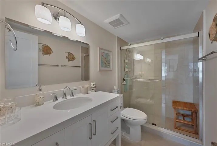 Full bathroom featuring toilet, visible vents, vanity, and a stall shower