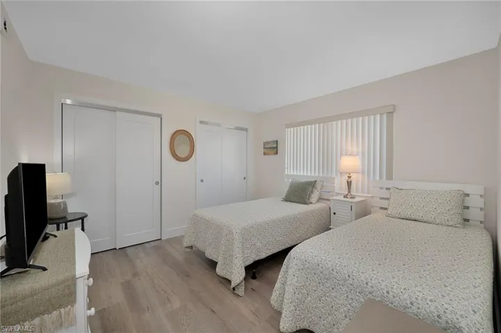 Bedroom with two closets, baseboards, and light wood-type flooring