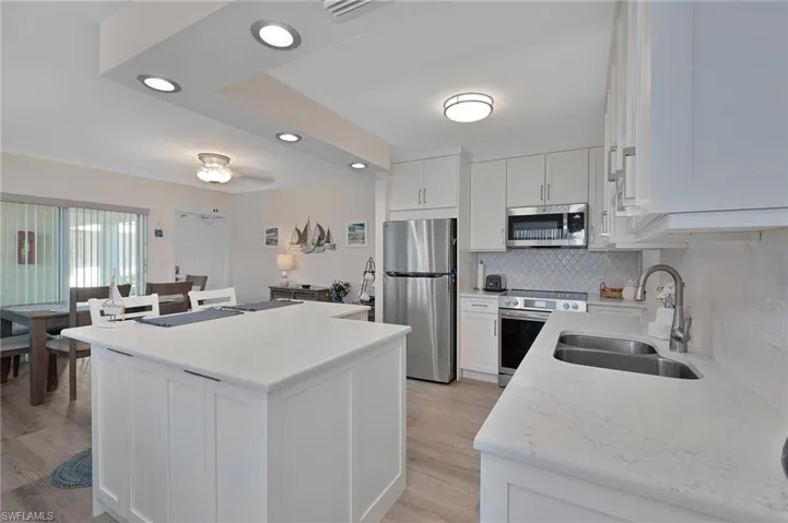 Kitchen with white cabinets, stainless steel appliances, a center island, a sink, and tasteful backsplash
