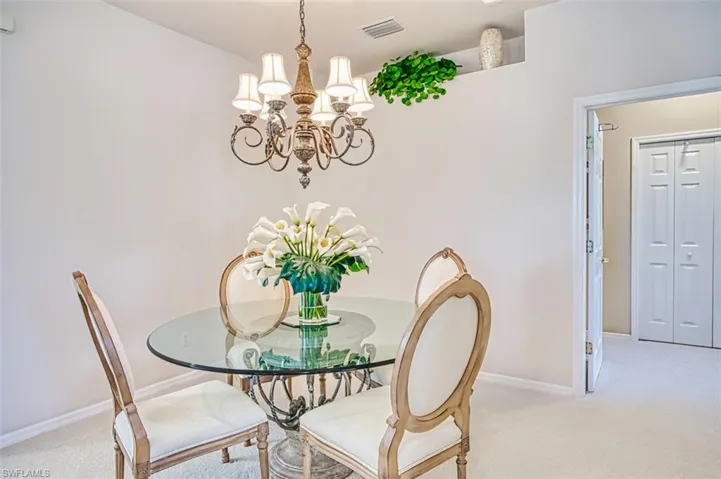 Dining area with light carpet and a chandelier