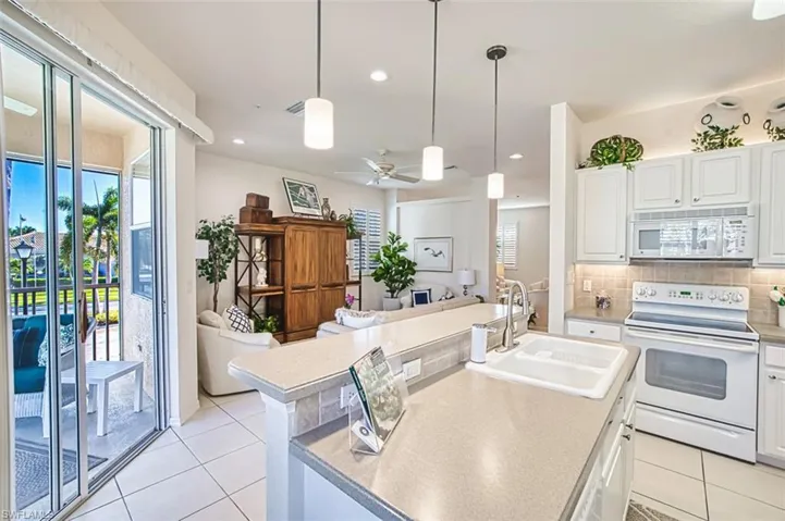 Kitchen with white cabinets, white appliances, hanging light fixtures, decorative backsplash, and recessed lighting