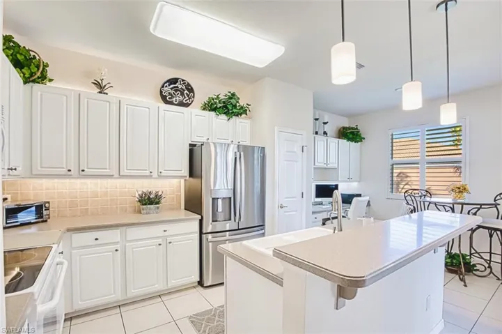 Kitchen featuring stainless steel refrigerator with ice dispenser, white cabinetry, range with electric cooktop, decorative light fixtures, and light tile patterned floors