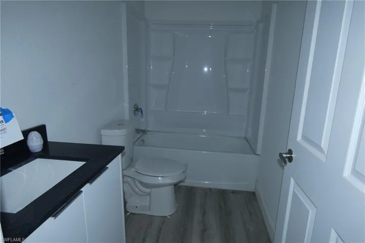 Bathroom featuring a white vanity with a dark countertop, an integrated sink, and chrome hardware