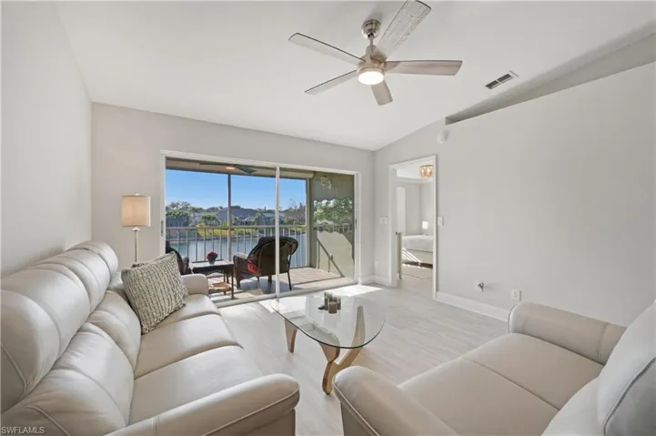 Living room featuring ceiling fan, wood finished floors, vaulted ceiling, and a water view