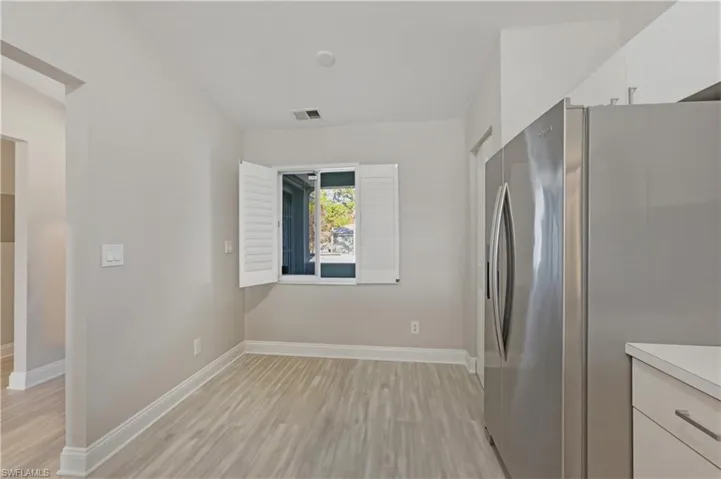Kitchen featuring stainless steel refrigerator with ice dispenser, white cabinets, light countertops, and light wood finished floors