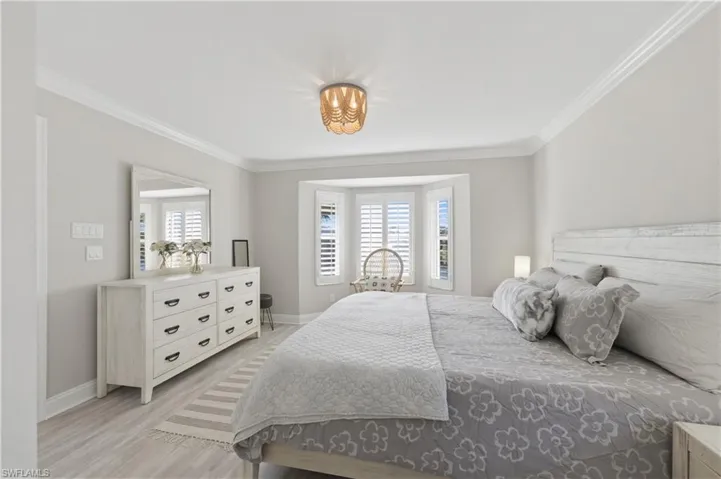 Bedroom featuring crown molding, multiple windows, and light wood-style flooring