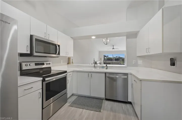 Kitchen featuring stainless steel appliances, light countertops, and white cabinets