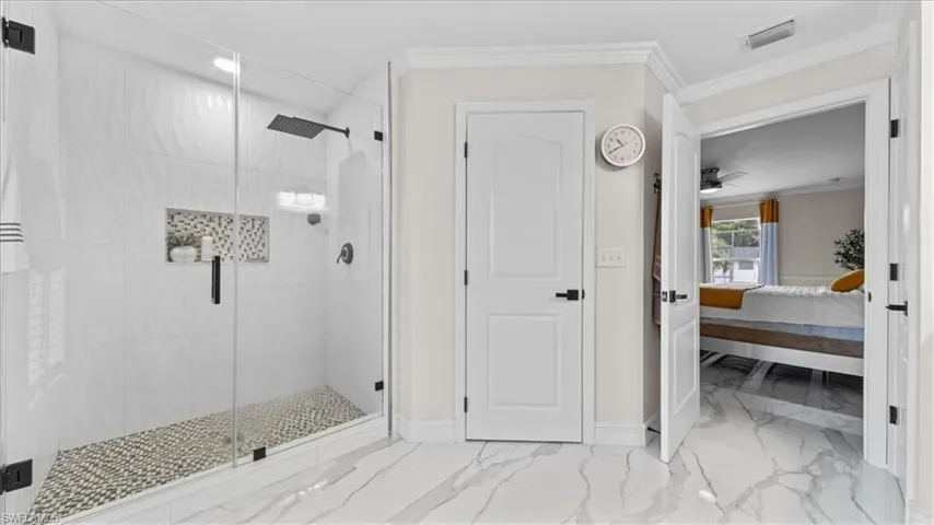 Full bath featuring ensuite bath, light marble finish flooring, a stall shower, ornamental molding, and a ceiling fan