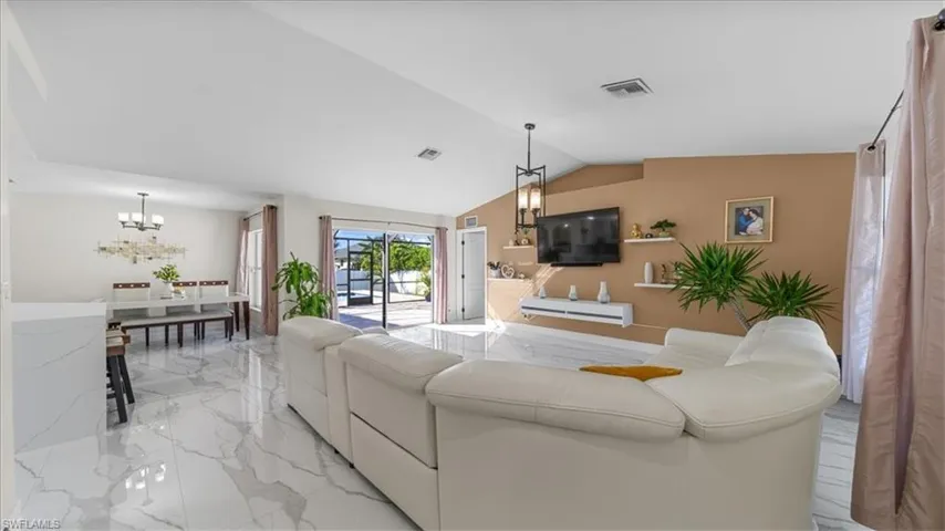 Living room featuring a chandelier, light marble finish flooring, and lofted ceiling
