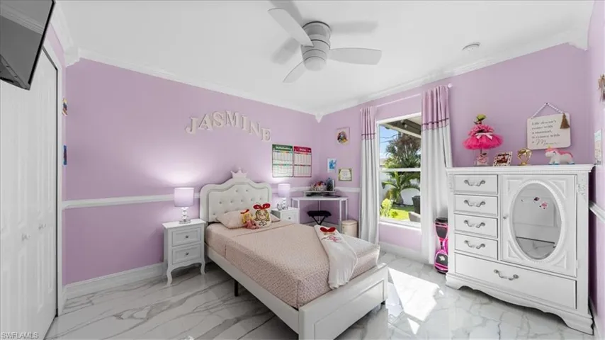 Bedroom with crown molding, light marble finish flooring, ceiling fan, and a closet