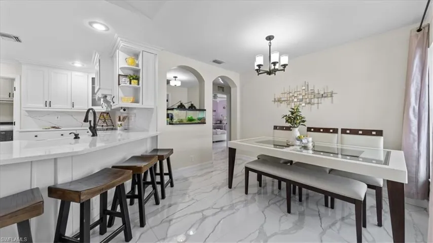 Dining area with arched walkways, light marble finish floors, recessed lighting, and a chandelier