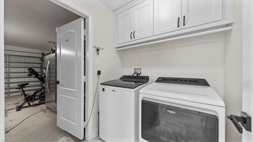 Laundry room featuring separate washer and dryer, cabinet space, and concrete floors