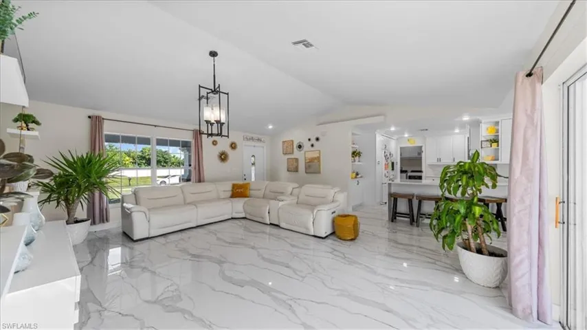 Living room with light marble finish flooring, lofted ceiling, and a chandelier