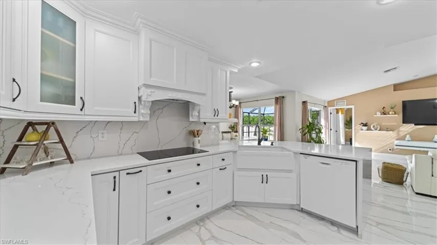 Kitchen featuring light marble finish flooring, open floor plan, white dishwasher, white cabinets, and tasteful backsplash