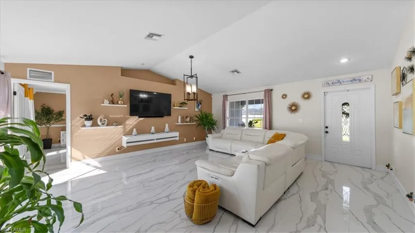 Living room featuring light marble finish floors and lofted ceiling