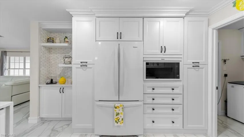 Kitchen featuring freestanding refrigerator, open shelves, light marble finish flooring, and white cabinetry