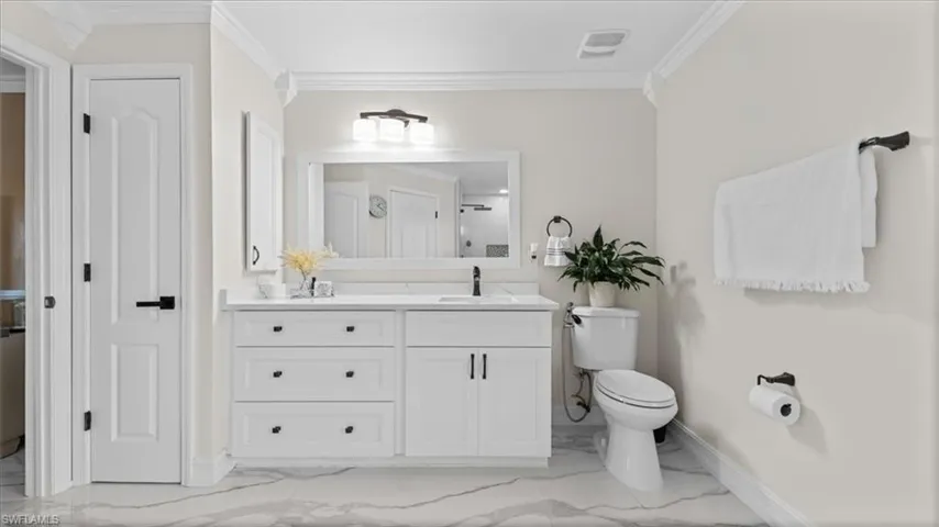 Full bathroom with vanity, ornamental molding, and light marble finish flooring