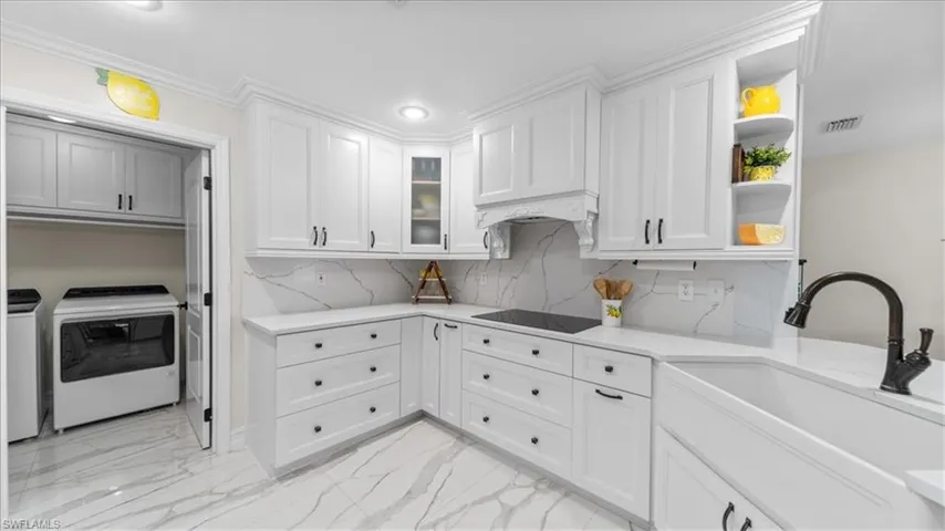 Kitchen with tasteful backsplash, open shelves, white cabinetry, light marble finish floors, and light stone countertops