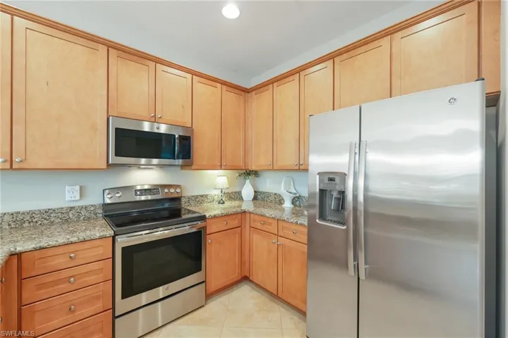 Kitchen with light stone countertops, light tile patterned floors, and stainless steel appliances