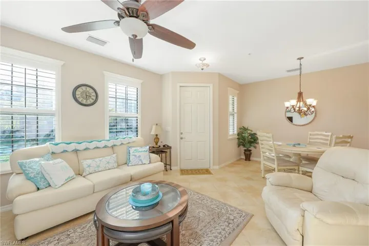 Living room with light tile patterned floors and ceiling fan with notable chandelier