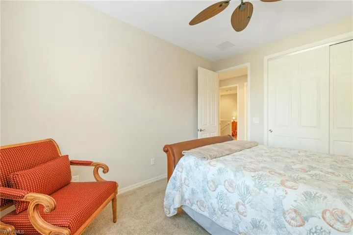 Carpeted bedroom with ceiling fan and a closet