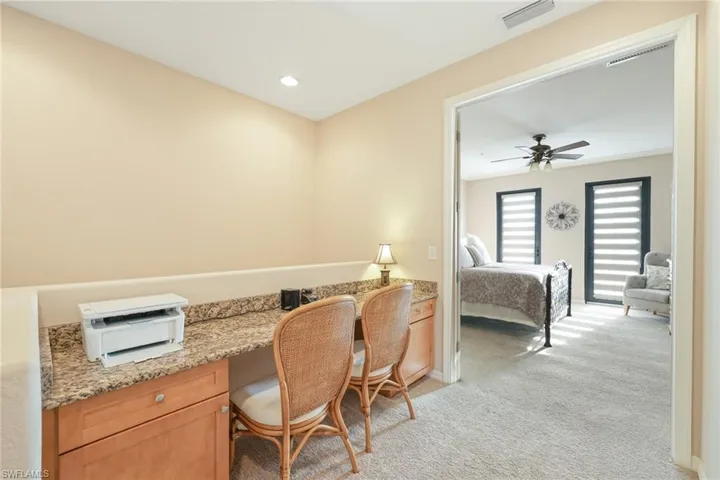 Carpeted home office featuring ceiling fan