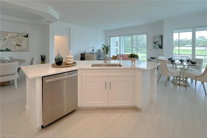 Kitchen featuring white cabinetry, dishwasher, light stone counters, a kitchen island with sink, and open floor plan
