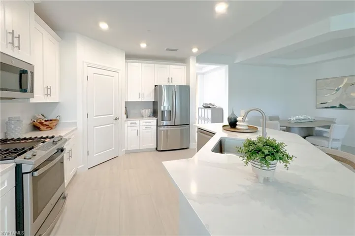 Kitchen featuring stainless steel appliances, white cabinetry, light stone countertops, and recessed lighting