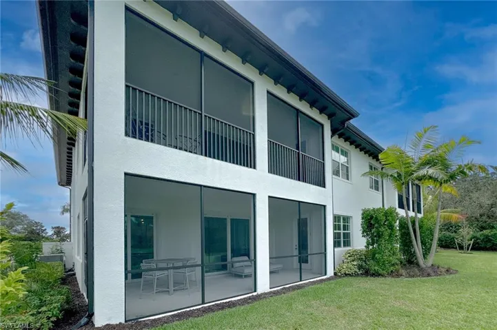Back of property featuring a balcony, stucco siding, and a lawn