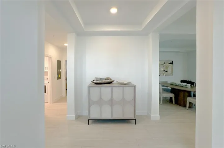 Corridor with recessed lighting, a raised ceiling, and light tile patterned floors