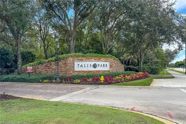 Community sign with view of scattered trees and a lawn