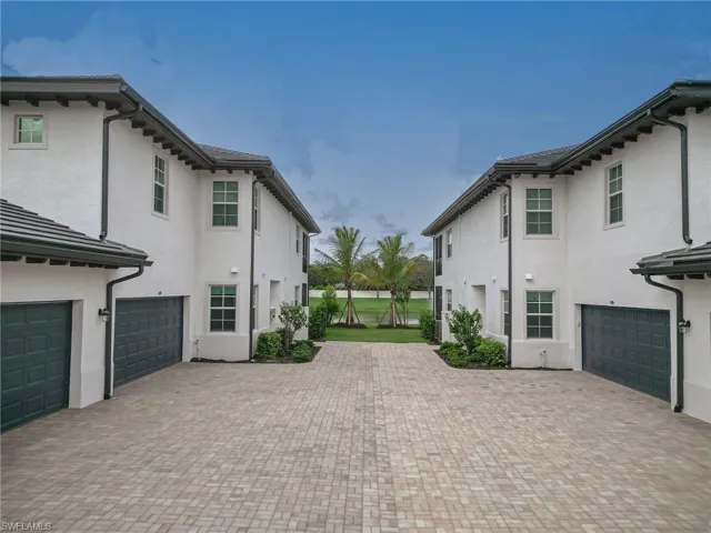 View of side of property featuring stucco siding, an attached garage, a gate, and decorative driveway