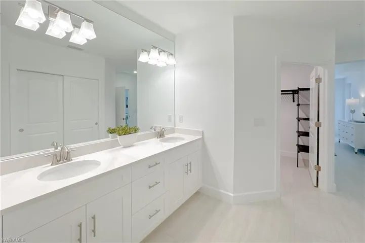 Bathroom with double vanity and baseboards