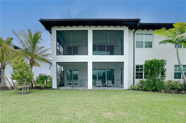 Back of property featuring a yard, a balcony, stucco siding, a sunroom, and a patio area