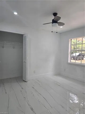 Unfurnished bedroom with a closet, baseboards, recessed lighting, ceiling fan, and marble finish floor