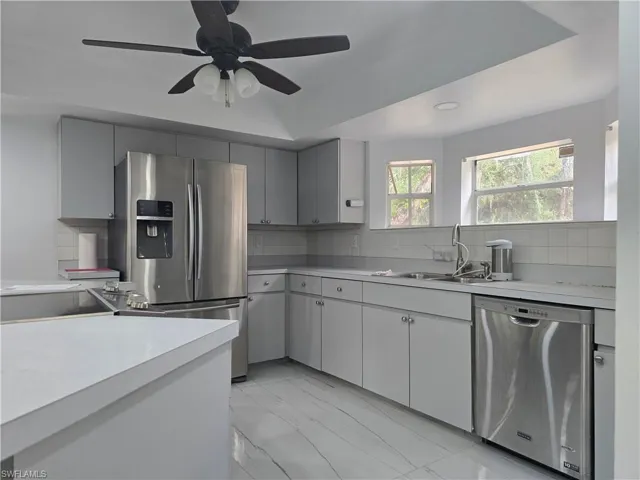 Kitchen with stainless steel appliances, light countertops, and backsplash