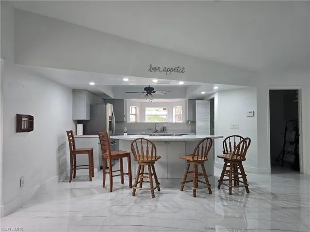 Kitchen featuring tasteful backsplash, a breakfast bar, a peninsula, gray cabinetry, and marble finish floor