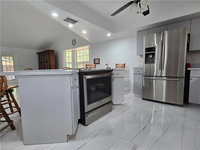 Kitchen with stainless steel appliances, visible vents, ceiling fan, and a healthy amount of sunlight
