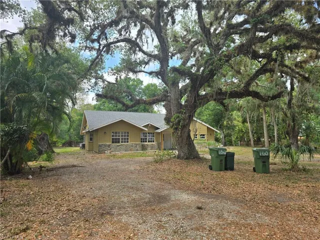 View of front of property with roof with shingles, driveway, and stone siding