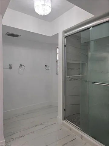 Full bath featuring marble finish floor, baseboards, visible vents, and a marble finish shower