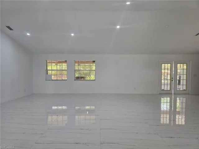 Empty room featuring visible vents, marble finish floor, vaulted ceiling, and recessed lighting