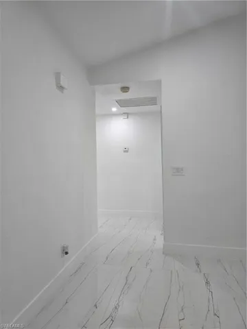Hallway with recessed lighting, marble finish floor, and baseboards