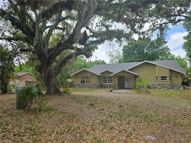 Ranch-style house with roof with shingles and stone siding