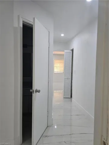 Corridor with recessed lighting, marble finish floor, and baseboards