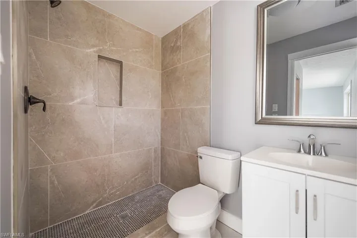 Bathroom with a tile shower, vanity, and toilet